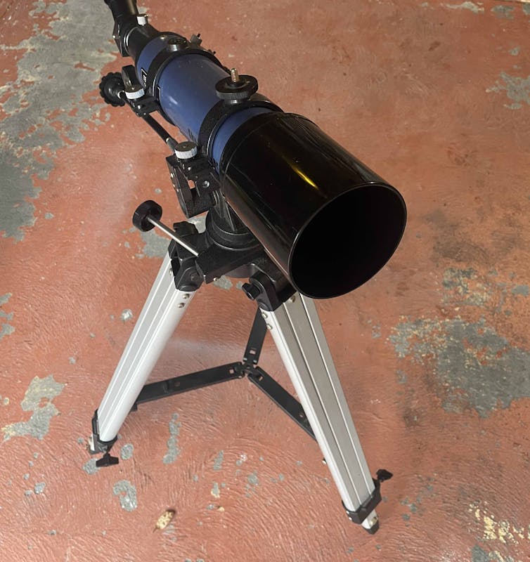 小さな望遠鏡がコンクリートの床上のシンプルなスタンドに置かれています